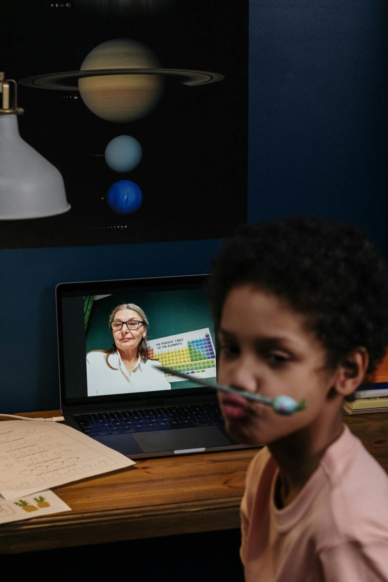 Child engaged in an online class with a teacher on a laptop, fostering education.